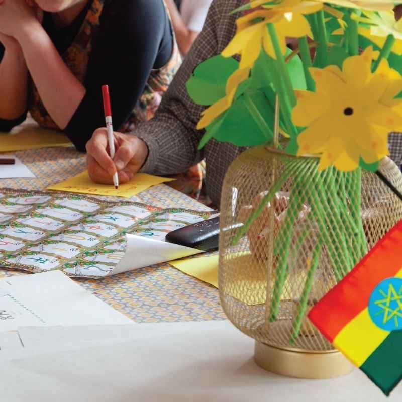Hands folding paper petals at the Adey Abeba workshop