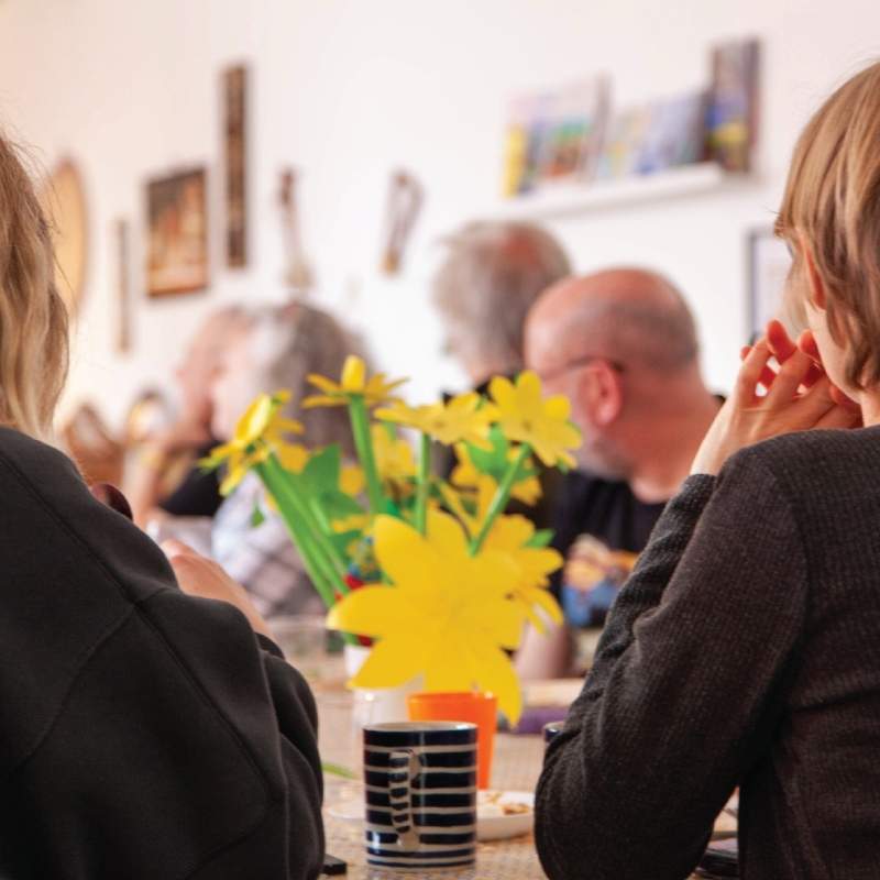 Guests gathered at the workshop table, cut paper and coffee
